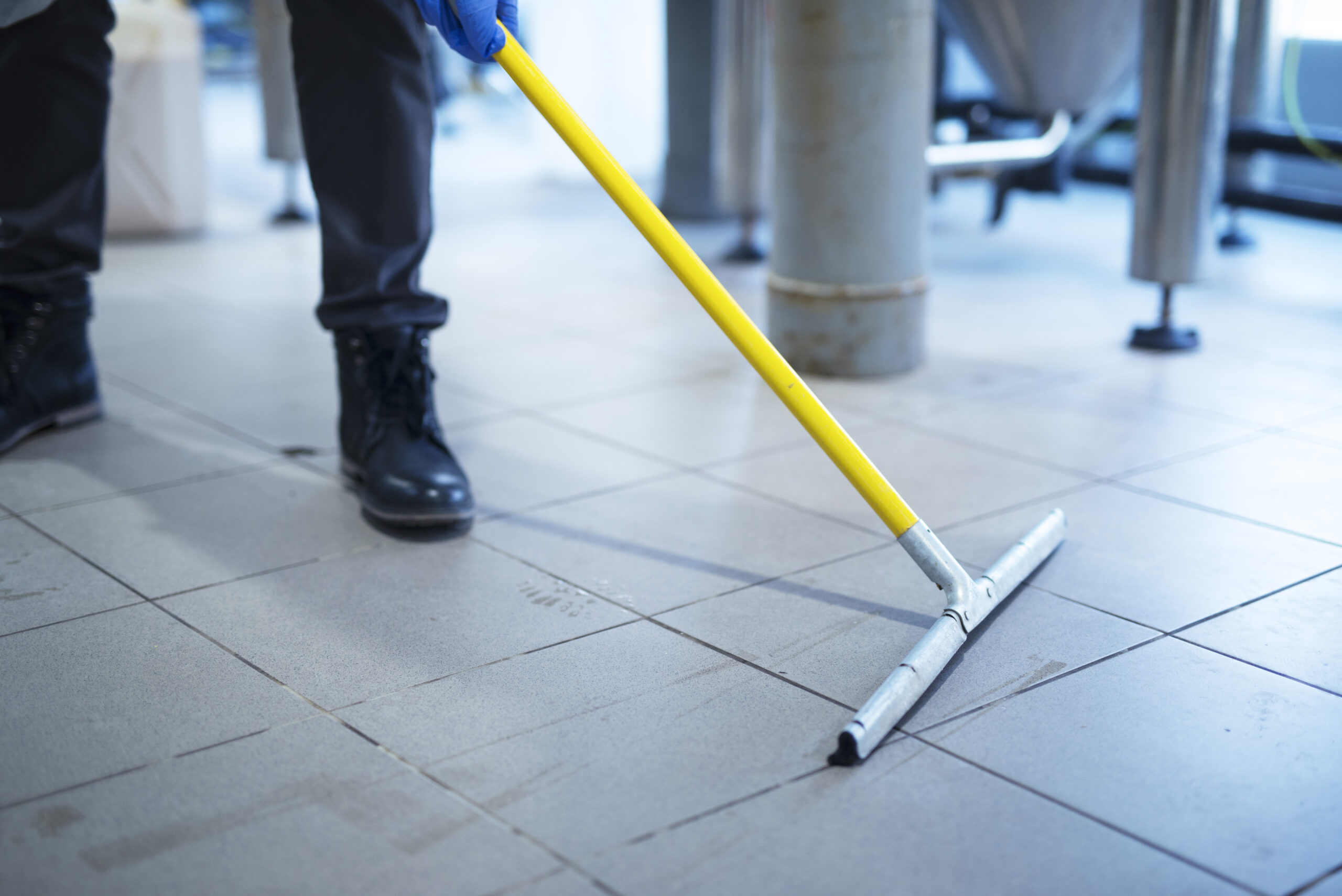 Close Up Of Mop Cleaning Industrial Plant Floor.